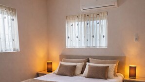 A bedroom with a large bed, bedside tables, an air conditioning unit, and curtains. - Apartments Diva "Flamingo" (Barber)