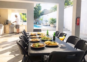 Ein Essbereich im Freien mit Grill, Pool und Feuerlöscher.