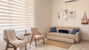 Una sala de estar con un sofá, dos sillones, una mesita con una planta y una alfombra.