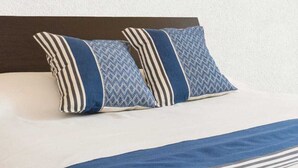Una cama con dos almohadas y una manta azul.