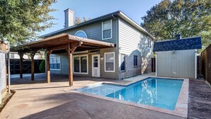 Ein Wohnhaus mit Swimmingpool, überdachter Terrasse und Ziegelaußenwand.