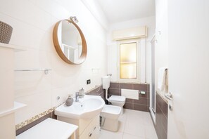A modern bathroom with a round mirror, white sink, toilet, and shower. - Villa Azzurra - Cala Mazzo Beach 5 Minutes Walk (Sicilia)