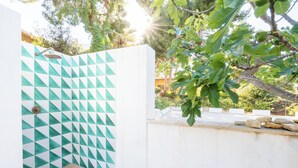 Un espacio de ducha con un diseño geométrico de azulejos, un banco de madera y una pared blanca.