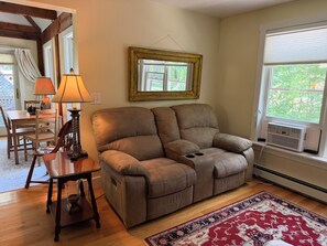 A living room with a brown leather sofa, a wooden table with chairs, a patterned rug, a lamp, and a window with blinds. - Secluded 1-bedroom apartment in charming York (York)