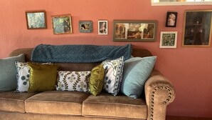 A brown sofa with multiple cushions, a blue throw blanket, and a patterned rug on the floor. - Welcoming 1-bedroom studio in vibrant Taos for your getaway (Taos)