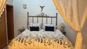 A bedroom with a bed, a nightstand, a lamp, and a wall-mounted decoration. - Welcoming 1-bedroom studio in vibrant Taos for your getaway (Taos)