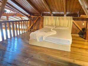 Une pièce avec un cadre en bois, un lit, un plancher en bois et une fenêtre.