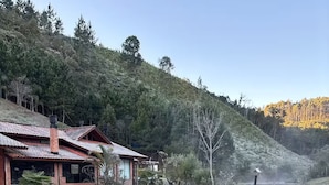 A rustic house with a tiled roof, surrounded by a pond and a wooden deck. - Chalet/Country House in the Serra SC area for friends and family, sleeps up to 15 people. (Anitápolis)