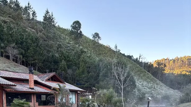 Ein rustikales Haus mit Ziegeldach, umgeben von einem Teich und einer Holzterrasse.