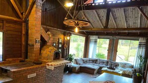 A rustic interior with a brick oven, a wooden ceiling, and a cozy seating area. - Chalet/Country House in the Serra SC area for friends and family, sleeps up to 15 people. (Anitápolis)