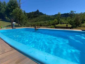 Une piscine rectangulaire à l’eau d’un bleu limpide, entourée d’une terrasse en bois.