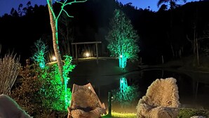An outdoor seating area with a fire pit, surrounded by chairs and illuminated trees. - Chalet/Country House in the Serra SC area for friends and family, sleeps up to 15 people. (Anitápolis)
