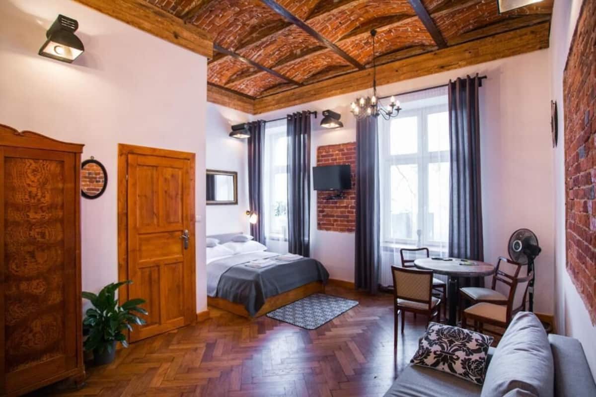 A cozy room with a bed, a sofa, a dining table, and a TV.