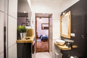 A modern bathroom with a large mirror, a sink with a bowl, and a small plant on a shelf. - Lovenovsky Apartments (Krakow)