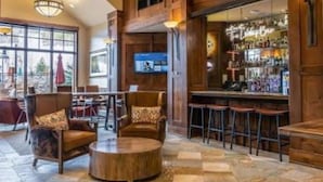 Una hall con pannelli in legno, un'area bar con sgabelli e un grande schermo.