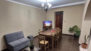 Een woonkamer met een bank, een salontafel, een televisie en een eettafel.