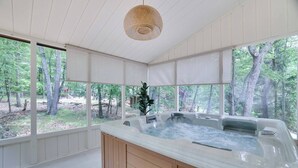 Un cuarto de spa con hidromasaje, ventanas amplias y vistas al bosque.