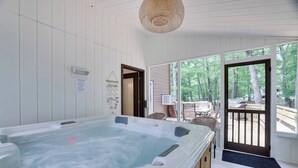 Una bañera de hidromasaje en una habitación con paredes blancas y ventanas amplias.