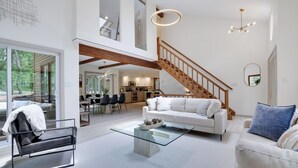 Amplia sala de estar con una escalera, comedor y cocina.
