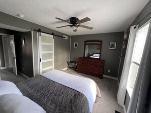 A bedroom with a bed, dresser, ceiling fan, and a door leading to another room. - Welcome to our Comfy Condo, on historic rte 66, 15 min from Ft Leonard Wood. (Richland)