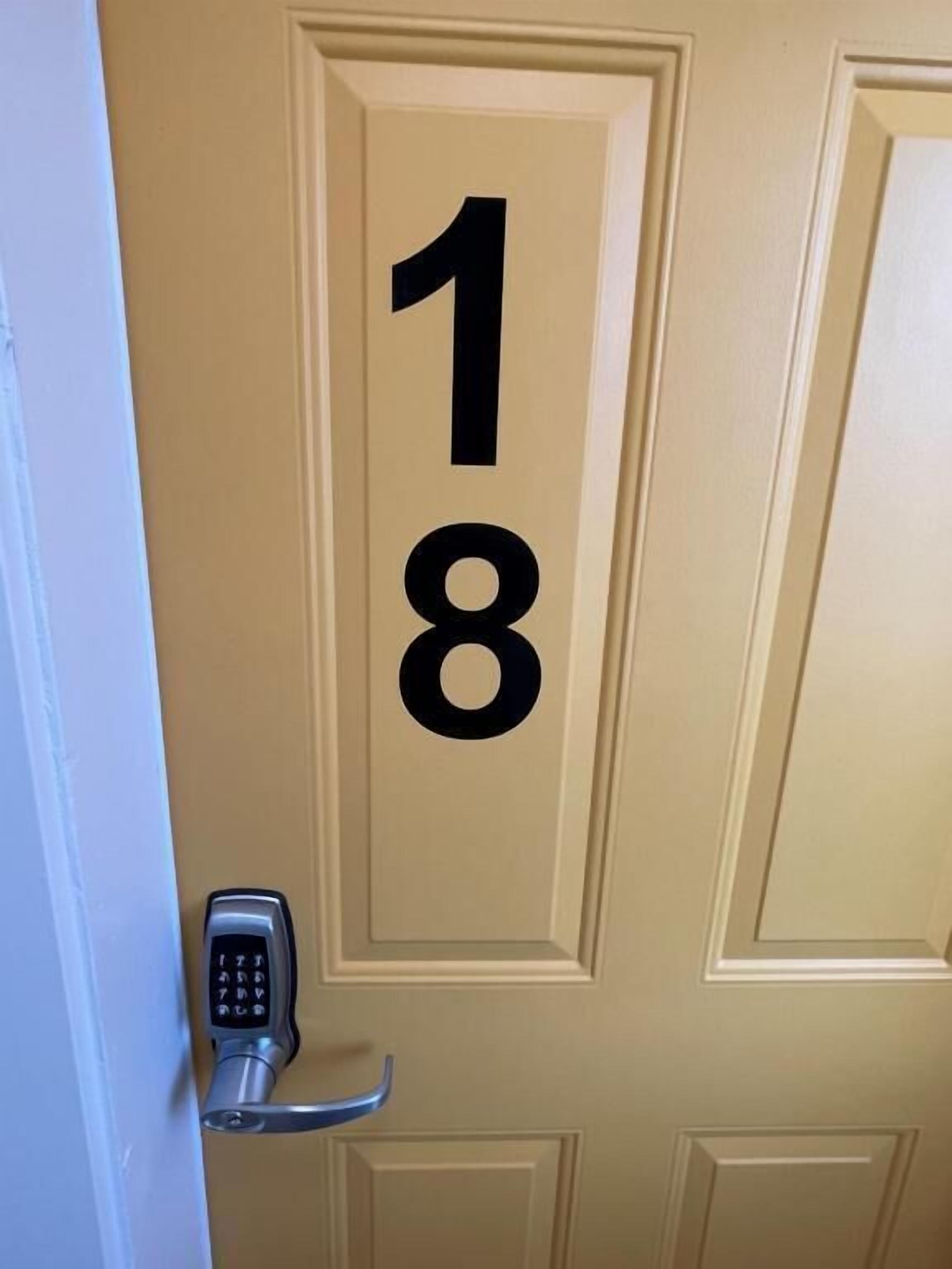 Een deur met het nummer 18 erop geschilderd, een deurbel en een codekluis.