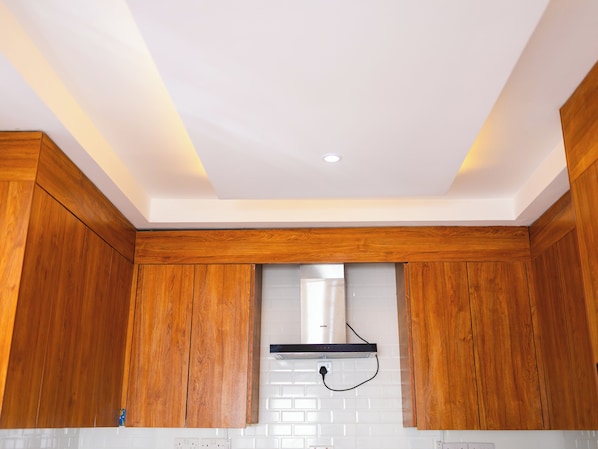 A kitchen with wooden cabinets, a white backsplash, and a stainless steel range hood.