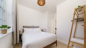 A bedroom with a bed, a wooden ladder, a potted plant, and a window. - Luxury duplex with 3beds/3baths. 15mins to Arsenal FC and Camden Town & Market (London)