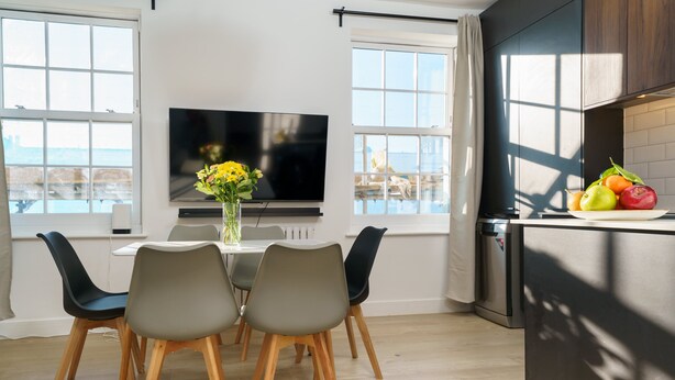 A modern kitchen with a dining area, large windows, and a flat-screen TV. - Luxury duplex with 3beds/3baths. 15mins to Arsenal FC and Camden Town & Market (London)