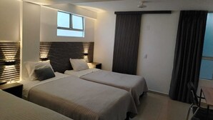 Ein modernes Hotelzimmer mit zwei Betten, einem Schreibtisch und einem großen Fenster.