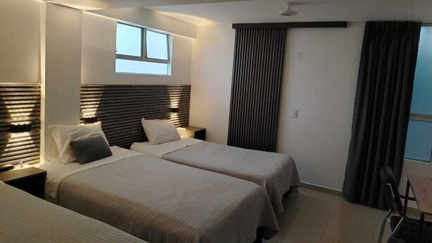 A modern hotel room with two beds, a desk, and a large window. - Hostal Mirador (Pisco)