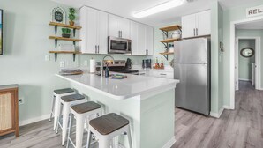 Eine moderne Küche mit weißen Schränken, einem Edelstahlkühlschrank und einer zentralen Kochinsel mit Barhocker.