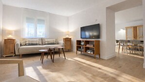 A modern living room with a sofa, a coffee table, a TV, and a bookshelf.