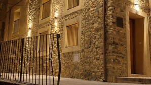 A stone building with multiple balconies and a lit street lamp.
