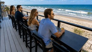 A deck with outdoor seating overlooking a beach.