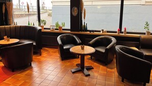 Un restaurante con asientos de cuero, una mesa pequeña y un ventanal con vista a la calle.