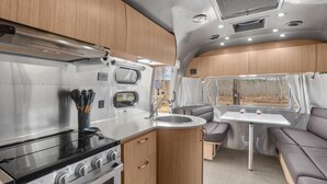 Une cuisine compacte pour camping-car, équipée d’une cuisinière, d’un évier et de placards en bois.