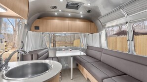 Un intérieur de camping-car compact comprenant un coin cuisine, un espace repas et un coin salon.