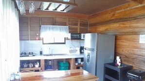 A compact kitchen with wooden cabinetry, a central island, and a hanging light fixture. - Cabin with amazing views of the Arenal Volcano (La Fortuna)