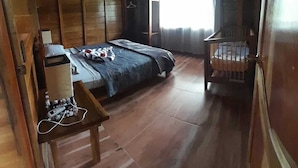 A wooden room with a bed, a chair, a small table, and a window with curtains. - Cabin with amazing views of the Arenal Volcano (La Fortuna)