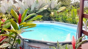 An outdoor swimming pool surrounded by lush tropical plants. - Cabin with amazing views of the Arenal Volcano (La Fortuna)