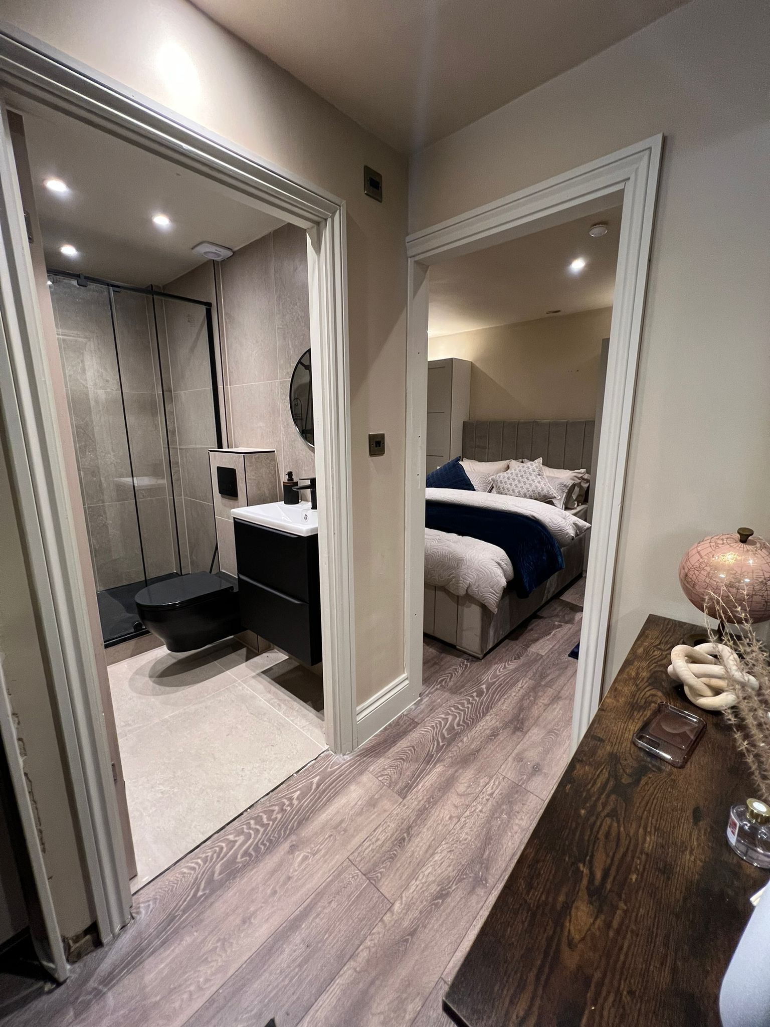 Une chambre à coucher moderne avec un grand lit, une table de chevet et un miroir.
