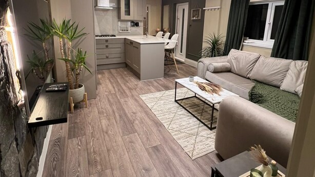 A modern living room with a sofa, coffee table, and a dining area with a kitchen in the background. - Modernized detached 2 bedroom Guest house. (Fulwood)