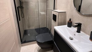 A modern bathroom with a glass-enclosed shower, a black toilet, and a white vanity with a mirror. - Modernized detached 2 bedroom Guest house. (Fulwood)