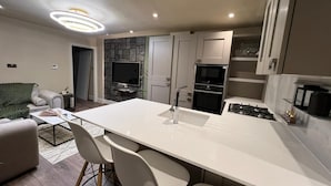 A modern kitchen with a central island, built-in oven, and a dining area with chairs. - Modernized detached 2 bedroom Guest house. (Fulwood)