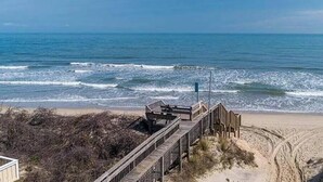 Una pasarela de madera que conduce a una playa con vista despejada al océano.