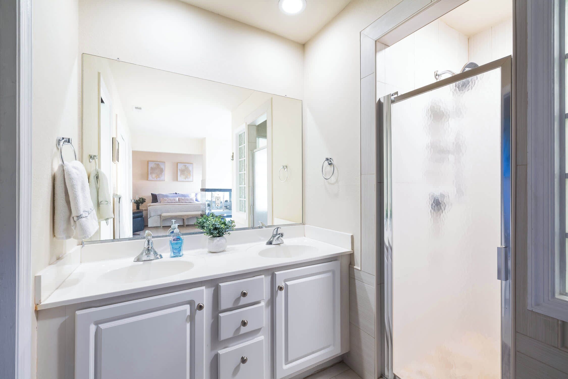 Un bagno con due lavandini, uno specchio grande e un box doccia in vetro.