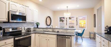 A modern kitchen with white cabinetry, stainless steel appliances, and a large island.