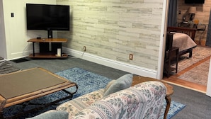 Una sala de estar con un televisor de pantalla plana grande, un sofá, una mesa de centro y un tapete estampado.