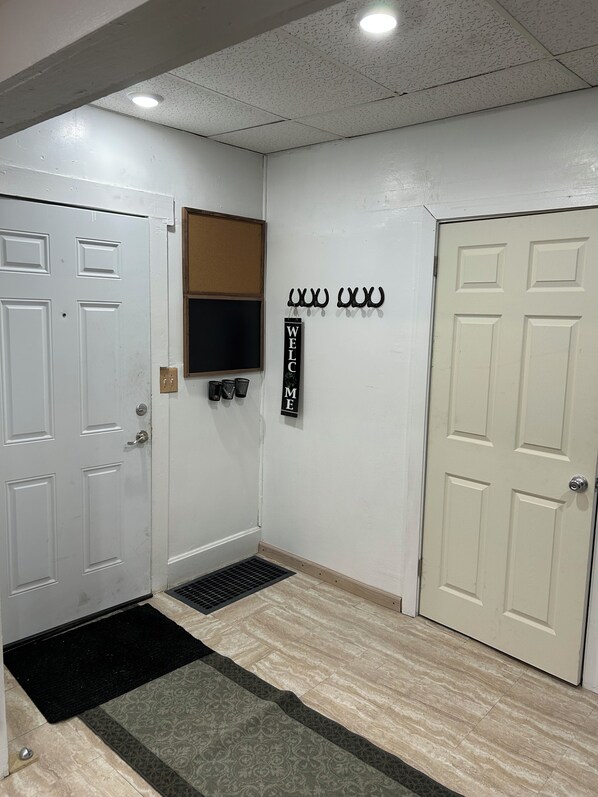 A clean, well-lit hallway with white doors, a welcome sign, and a coat rack.