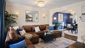 A modern living room with a brown leather sofa, a black coffee table, and a piano in the background.